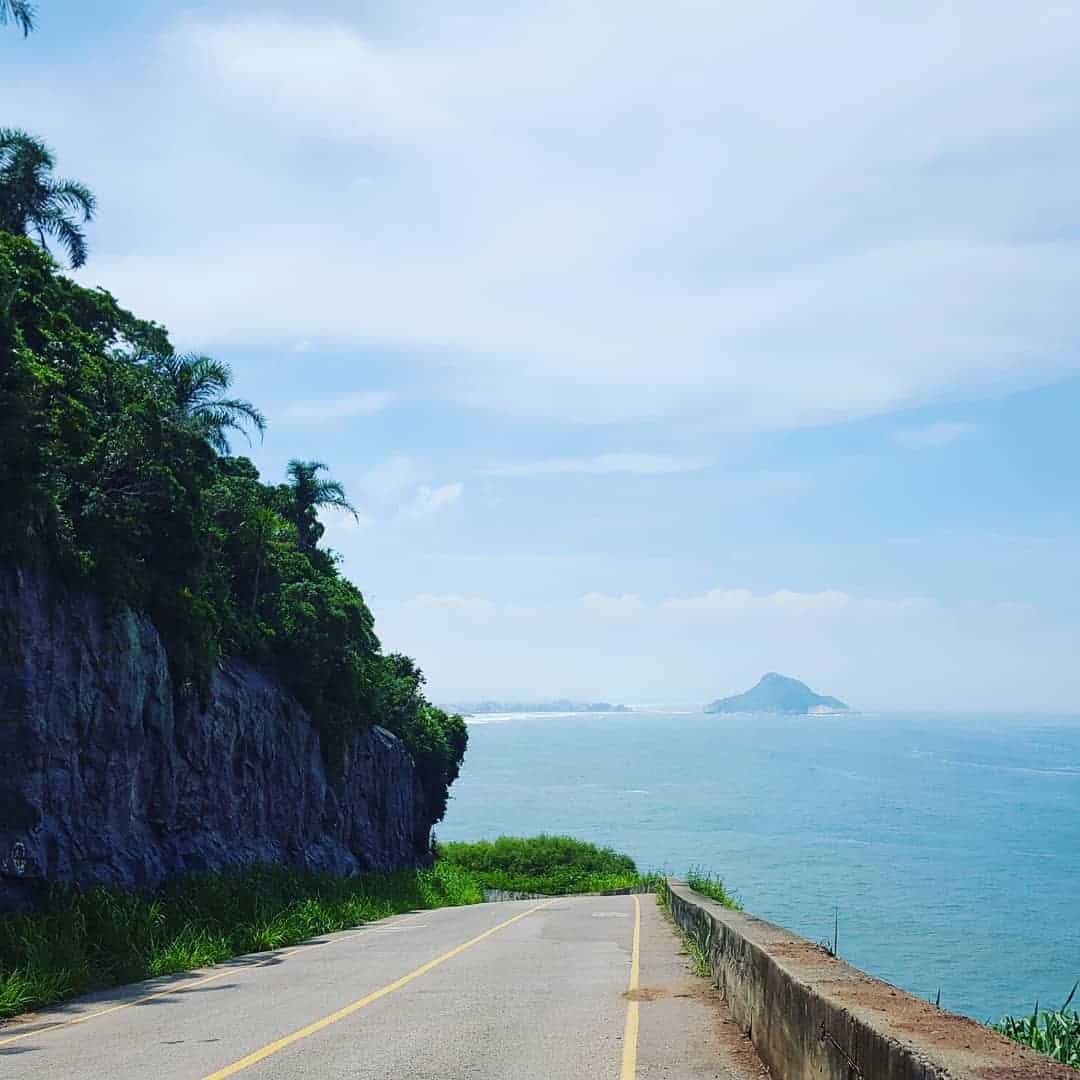 Prainha Beach in Rio de Janeiro showing pristine crescent-shaped bay surrounded by lush Atlantic rainforest with surfers riding perfect waves