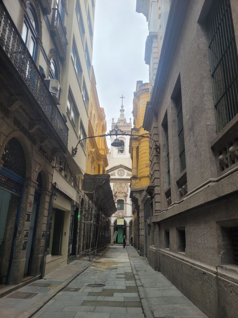 Narrow cobblestone alley in Rio de Janeiro's historic city center leading to a colonial-era church