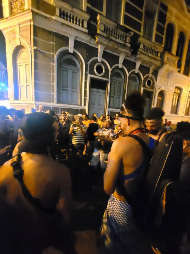 Brass band musicians playing for revelers in front of a historic building at a free street bloco in Rio