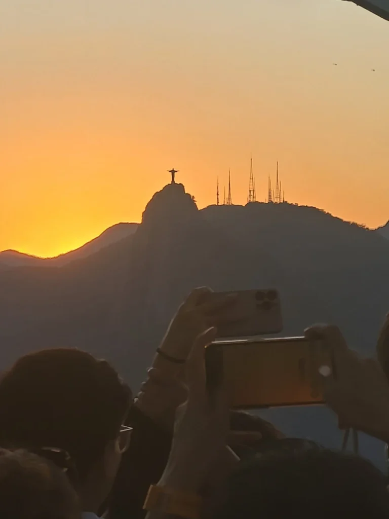 Christ the Redeemer silhouetted against an orange sunset sky, seen from Sugarloaf Mountain in Rio de Janeiro