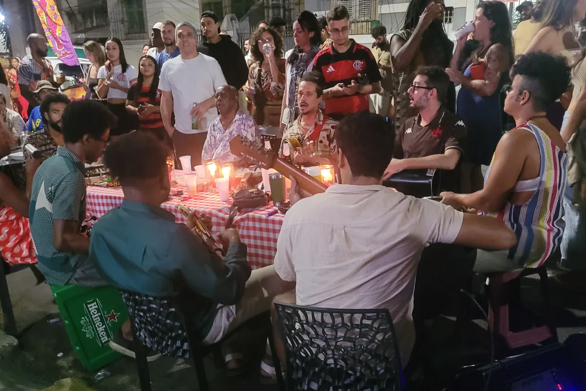 Locals playing live samba around a table at a street samba circle in Rio de Janeiro at night