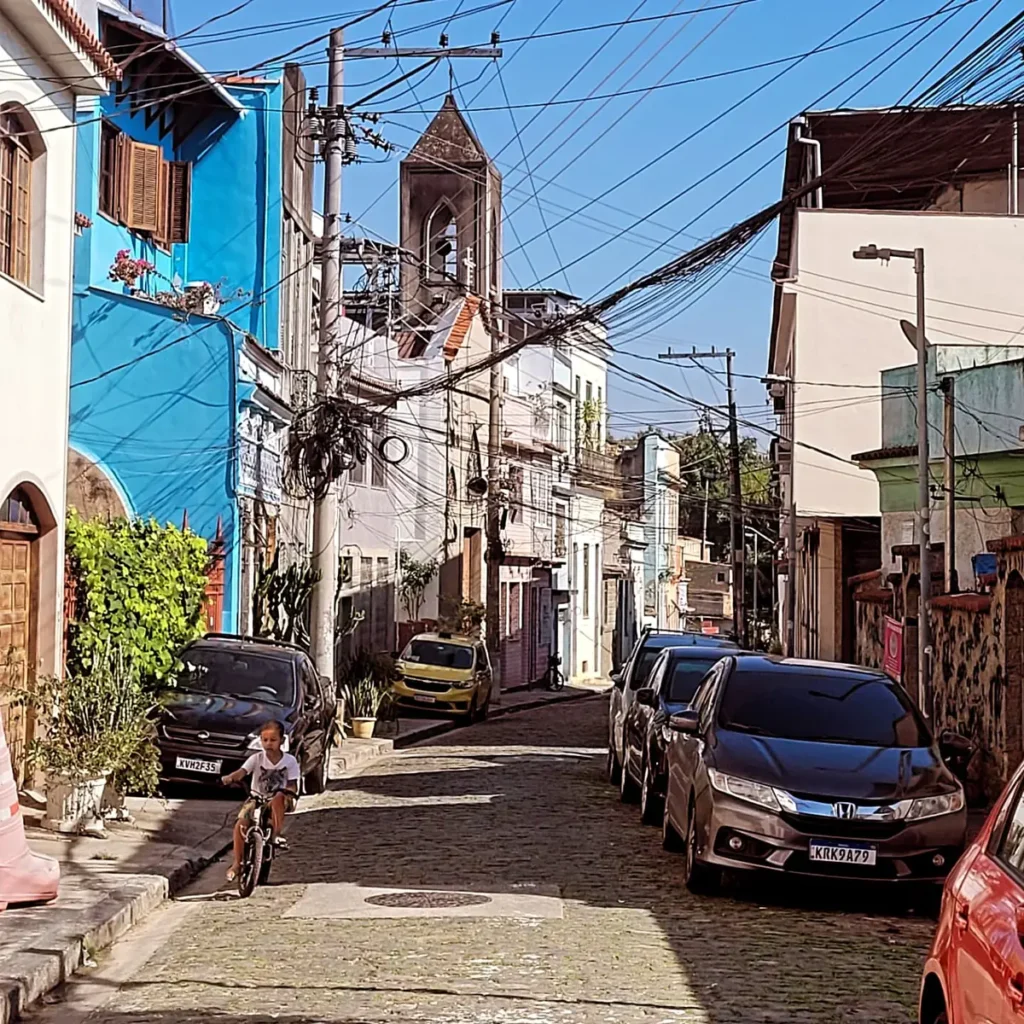 Cobblestone street with colorful colonial houses and a church bell tower in a historic neighborhood of Rio de Janeiro