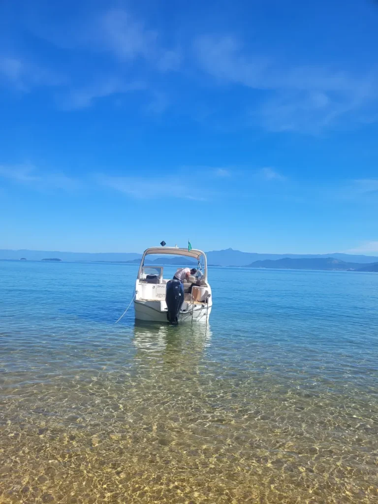Private boat anchored in crystal-clear water on a slow day trip to Ilha Grande