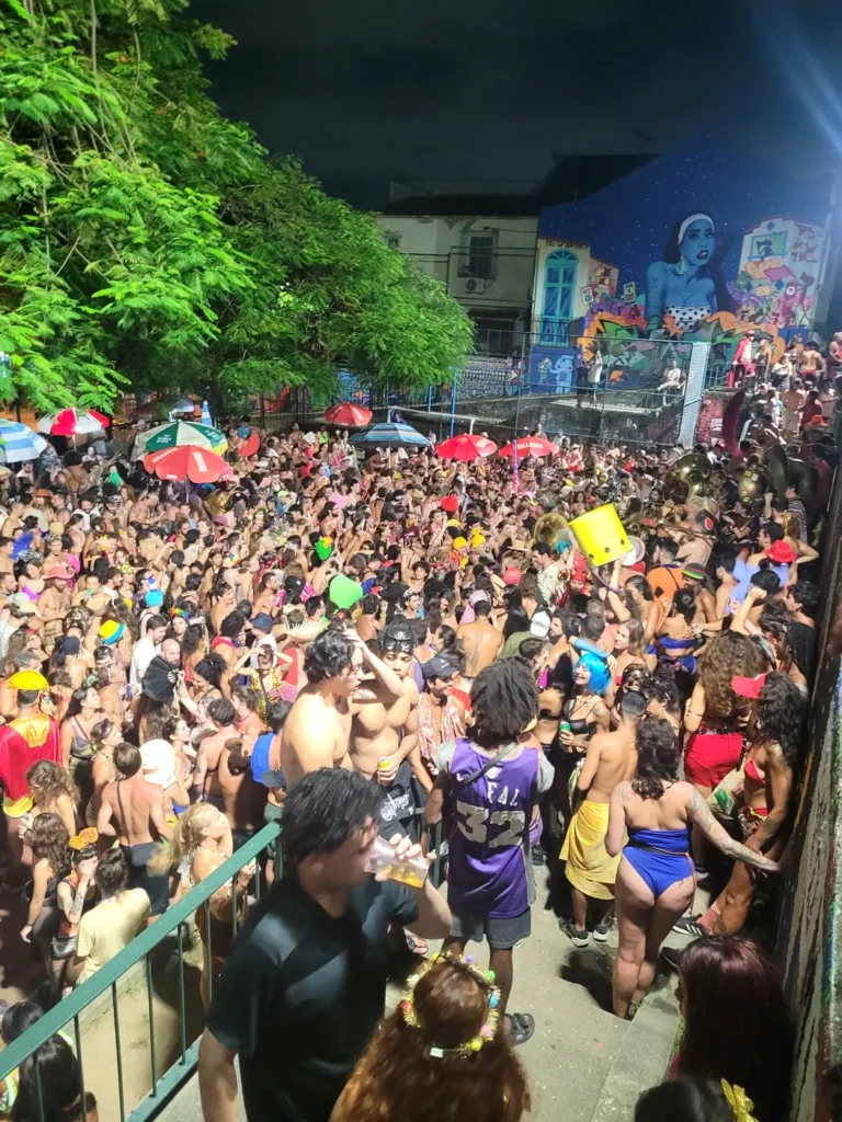 Thousands of costumed revelers dancing at a night street bloco with a brass band during Rio de Janeiro Carnival